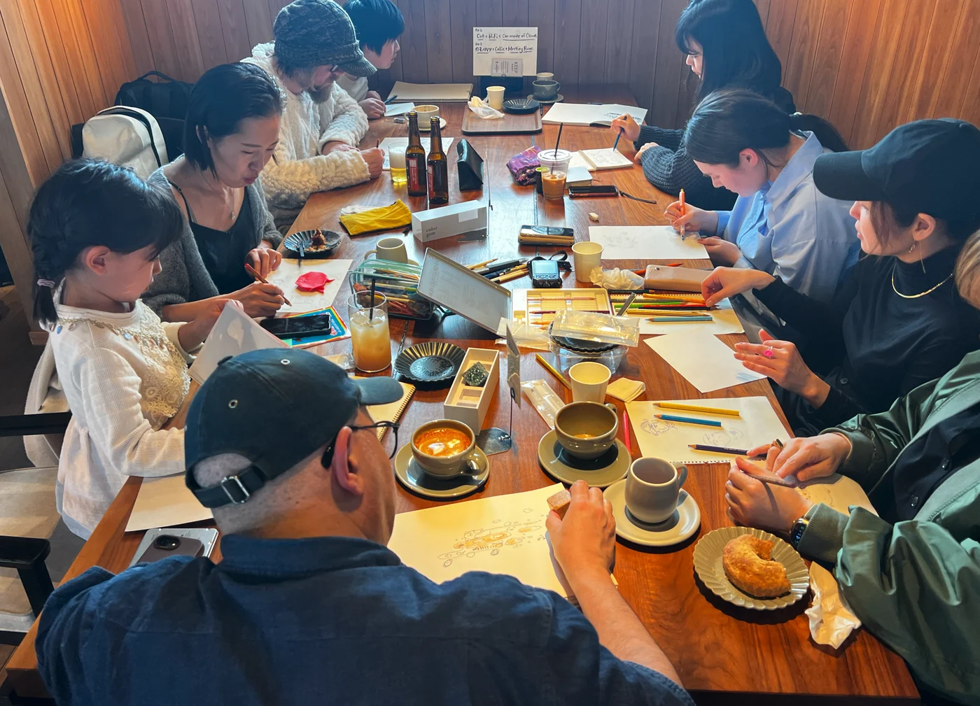 An Odd Pencils group drawing together around a long table.